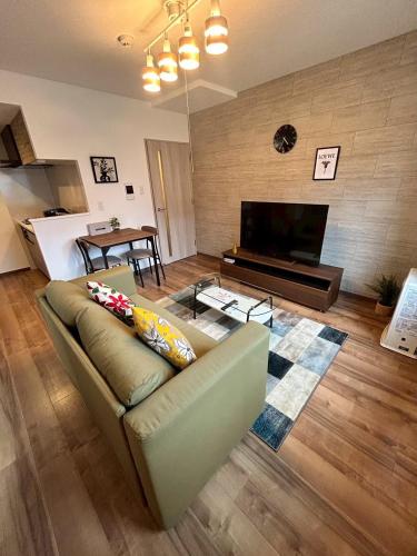 a living room with a couch and a flat screen tv at Stisfy サティスファイ in Chitose