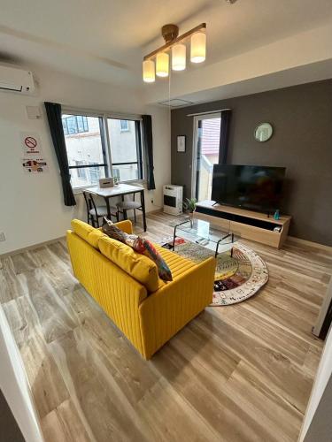 a living room with a yellow couch and a television at Stisfy サティスファイ in Chitose