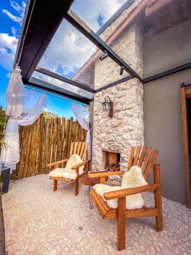 a patio with two chairs and a stone fireplace at Pousada Villa Dois Amores in Lindóia