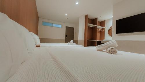a large bedroom with two beds and a flat screen tv at Arraial Concept Hotel in Arraial do Cabo