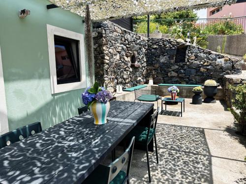 a table with a vase of flowers on a patio at THE L lodge, ocean view private garden Cottage in Ribeira Brava