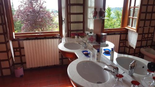 ein Badezimmer mit zwei Waschbecken und zwei Fenstern in der Unterkunft Allevamento B&B in Pozzolgroppo