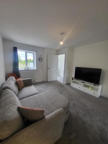 a living room with a couch and a flat screen tv at Modern 3-Bed House in Rotherham, WiFi, Garden & Free Parking in Kimberworth
