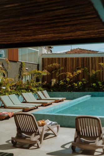 a row of lounge chairs next to a swimming pool at Arraial Concept Hotel in Arraial do Cabo