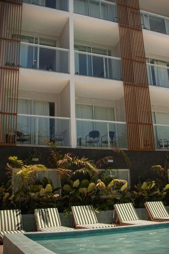 a hotel with chairs and a swimming pool in front of a building at Arraial Concept Hotel in Arraial do Cabo