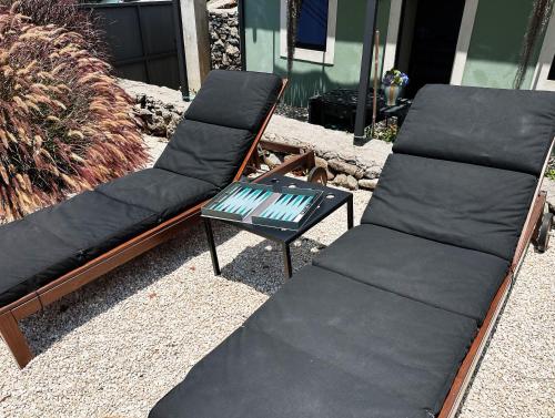 two chairs and a table on a patio at THE L lodge, ocean view private garden Cottage in Ribeira Brava