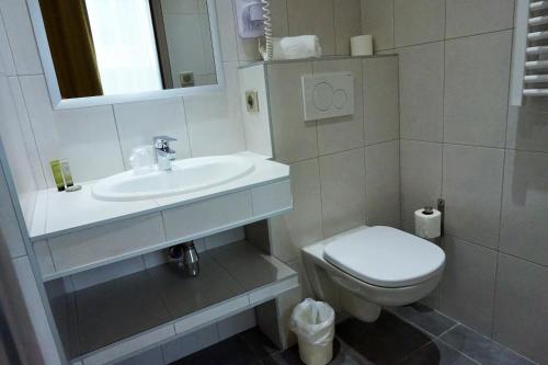 a white bathroom with a sink and a toilet at Hotel de la Couronne in Aix-les-Bains