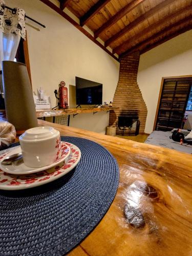 a coffee cup and saucer sitting on a wooden table at Recanto do Baú - Chalé aos pés da Pedra do Baú in São Bento do Sapucaí