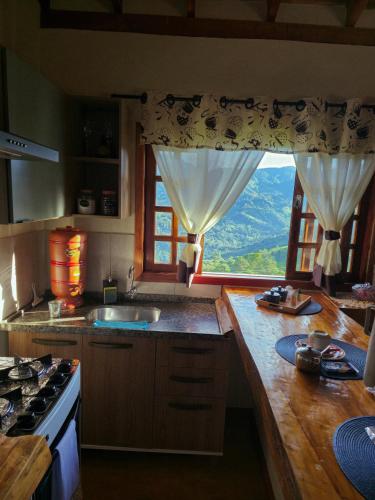a kitchen with a sink and a large window at Recanto do Baú - Chalé aos pés da Pedra do Baú in São Bento do Sapucaí
