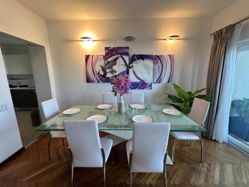 a dining room table with white chairs and a vase of flowers at Paceville Sandy Beach with Jacuzzi & Free Parking in St Julian's
