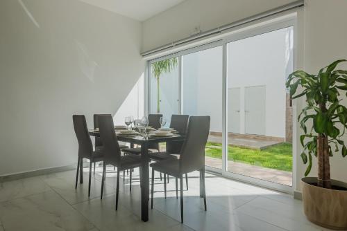 Un comedor con mesa y sillas y una gran ventana. en Malibu Residential 3BD Shalva, en Cozumel