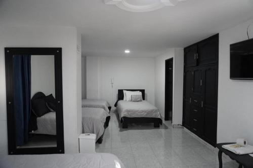 a white room with two beds and a mirror at Hotel Ariston in Pasto