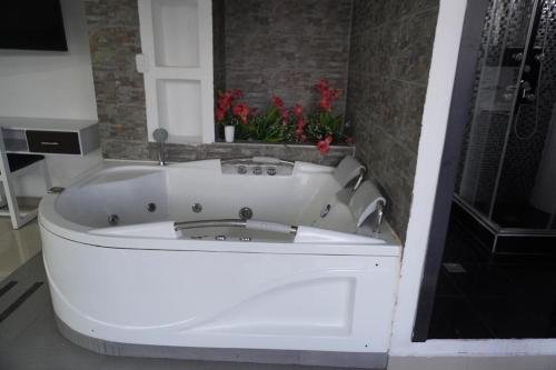 a white bath tub in a bathroom with red flowers at Hotel Ariston in Pasto
