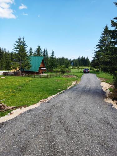a dirt road with a barn and a car on it at Holiday chalet Asterix in Žabljak