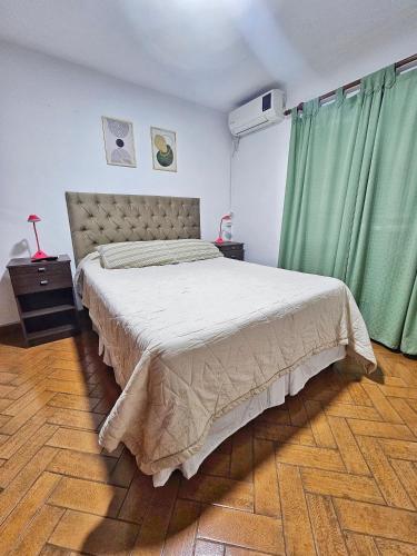 a bedroom with a large bed with green curtains at Chalet Salta in Salta