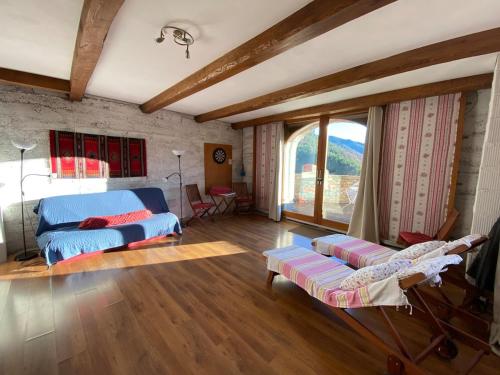 - un salon avec un lit bleu et une grande fenêtre dans l'établissement Gîte Lou Clapas dans village perché du Parc des Grands Causses, à Nant