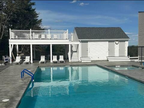 a swimming pool with chairs and a house at Cedar Lodge Room-Private Balcony Close to Weirs! in Laconia