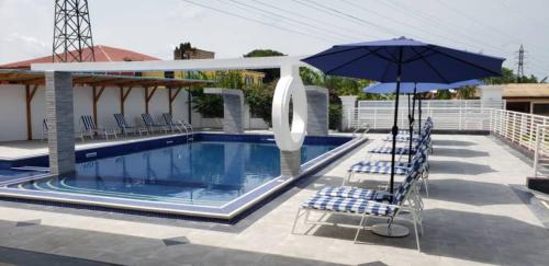 two chairs and an umbrella next to a swimming pool at Park Springs Hotel in Cape Coast