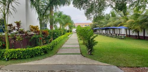 a walkway through a park with palm trees and a building at Park Springs Hotel in Cape Coast