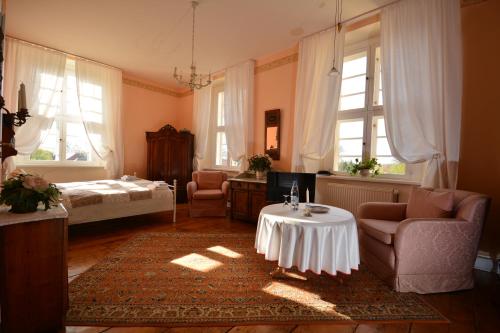 ein Wohnzimmer mit einem Tisch und einem Bett in der Unterkunft Jagdschloss Quitzin in Grimmen