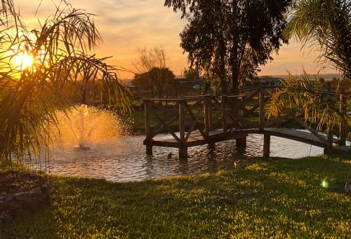 a wooden bridge over a pond with a fountain at Casa com piscina em São Gabriel RS in São Gabriel