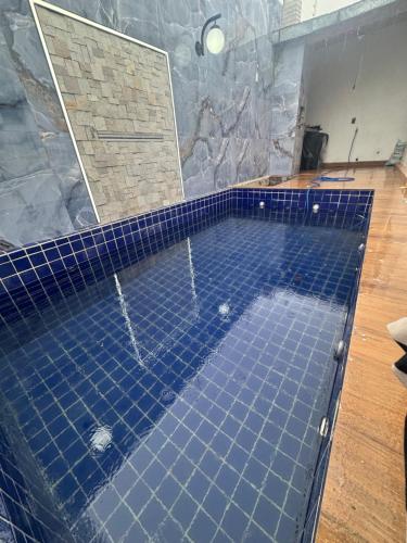 einen Pool mit blauen Fliesen im Bad in der Unterkunft Moderno 3 quartos piscina e sinuca luxo in Campina Grande