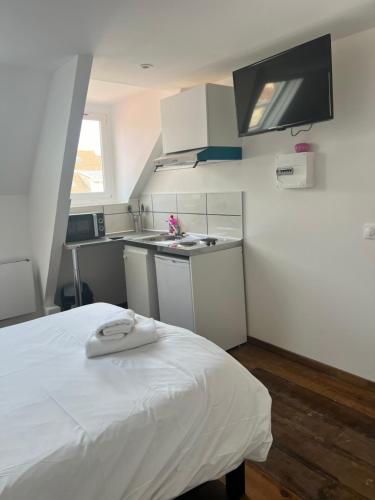 une chambre avec un lit blanc et une cuisine dans l'établissement Royal appart city 3, à Calais