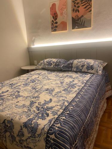 a bed with a blue and white blanket and pillows at Hotel Casa Blanca in Mossoró