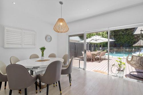 a dining room with a table and chairs and a pool at Poolside 3BR Coastal Retreat in Avalon Beach in Whale Beach