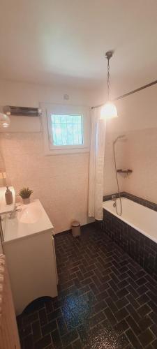 une salle de bain avec une baignoire et un lavabo et une baignoire dans l'établissement Charmante maison de vacances, à Vallon-Pont-dʼArc