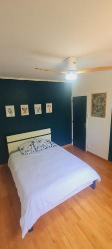 une chambre avec un lit blanc avec un mur bleu dans l'établissement Charmante maison de vacances, à Vallon-Pont-dʼArc
