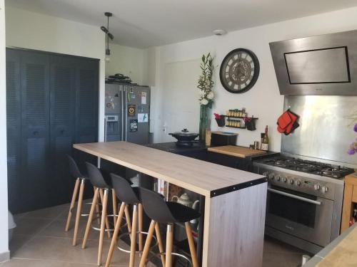 - une cuisine avec une cuisinière et un comptoir avec des tabourets dans l'établissement Bastide avec jardin arboré, piscine, proche plages, à Cournonsec