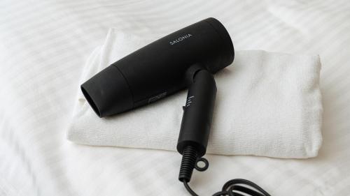 a black hair dryer sitting on top of a bed at 別府ホテル塒 Beppu Hotel Negura in Beppu