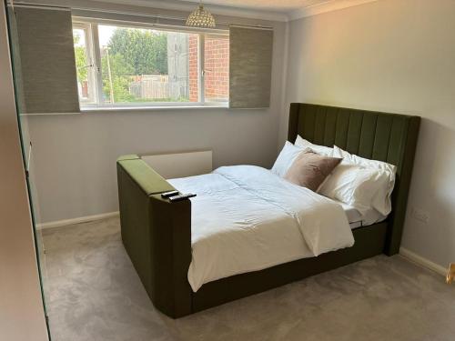 Una cama con cabecero verde en un dormitorio. en Home in Milton Keynes, en Milton Keynes