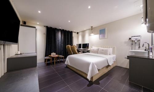 a bedroom with a large white bed and a desk at Hotel Yaja Cheongju Terminal Branch in Cheongju
