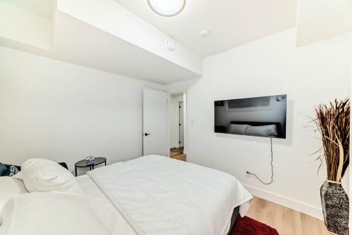 une chambre blanche avec un lit et une télévision au mur dans l'établissement Ola's Place, à Edmonton