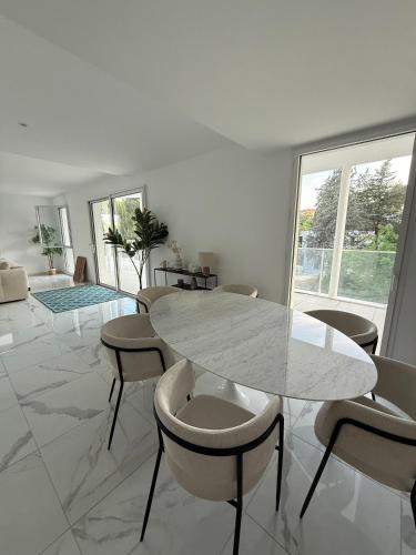 - une salle à manger blanche avec une table et des chaises en marbre dans l'établissement Appartement Neuf Marseille Plage, à Marseille
