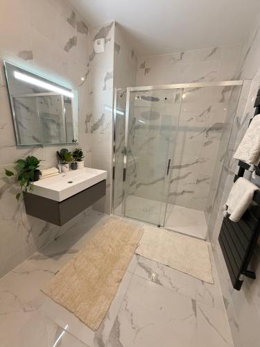 une salle de bain blanche avec une douche et un lavabo dans l'établissement Appartement Neuf Marseille Plage, à Marseille