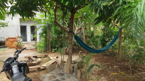 a motorcycle parked next to a tree with a hammock at Casa Canela in Cavalcante