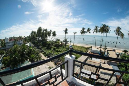 a balcony with a view of the beach and palm trees at Aloha Hotel Mũi Né in Ấp Thiện Sơn