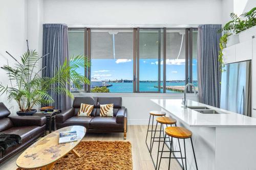 a kitchen and living room with a couch and a table at Waterfront Loft at Quay, Walk to Ferry & Train in Auckland