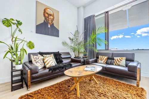 a living room with a leather couch and a table at Waterfront Loft at Quay, Walk to Ferry & Train in Auckland