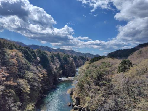 a river in the middle of a valley with trees at Wa no oto 和の音交流館 鬼怒川宿 in Nikko