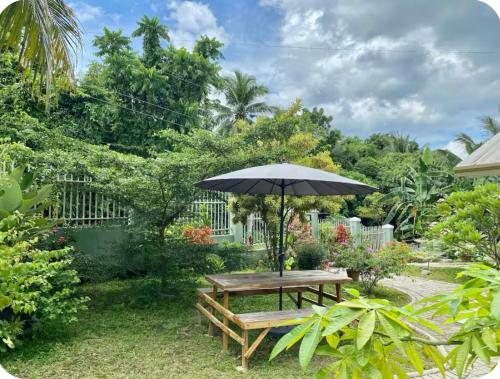 a wooden picnic table with an umbrella in a garden at Lucia’s Place in Tanauan