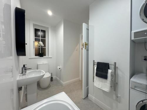 a white bathroom with a sink and a toilet at Discerning in Thorndon in Wellington