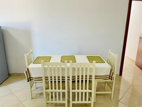 a white table with chairs and a white wall at EasyTrip Family - City Center in Divjakë