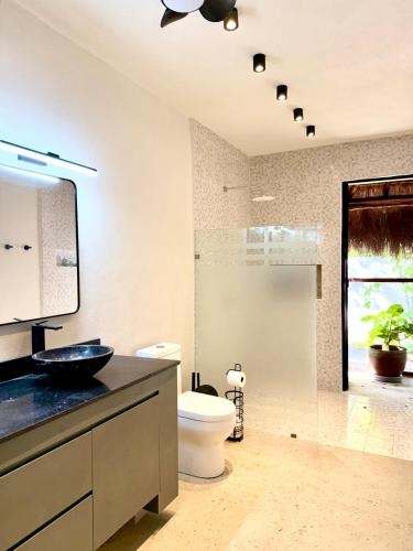 een badkamer met een wastafel en een toilet en een raam bij La Cueva De Piedra in Puerto Morelos