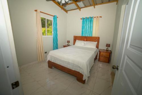 a bedroom with a bed and a window with blue curtains at JARABACOA villa Almonte in Jarabacoa