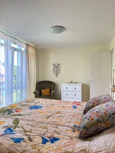 a bedroom with a large bed and a chair at Apartamentai Taikos 24 in Nida