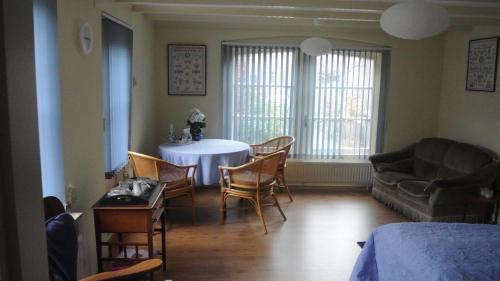een woonkamer met een tafel en stoelen en een bank bij B&B de Noordenberg in Holten
